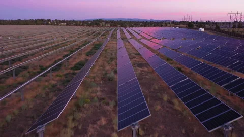 Low forward tracking over solar panels with colorful sunset sky reflections Stock Footage 160932009