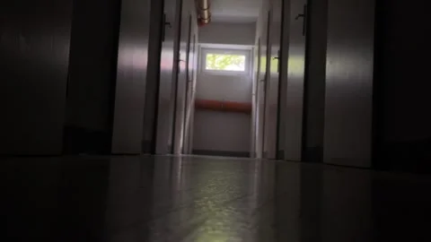 Low ground perspective corridor leading to small high window with pipe and floor Vidéo 344882066