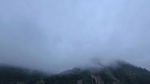 Low hanging clouds and thick fog rolling rapidly over a forested mountain ridge 스톡 동영상 344817957