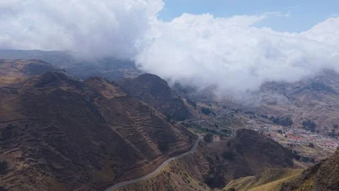 Low hanging clouds drifting above Andean peaks, unveiling lush valley with Stock Footage 308393195