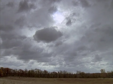 Low hanging white and gray clouds moving across barren dry meadow. Stock Footage 86751089
