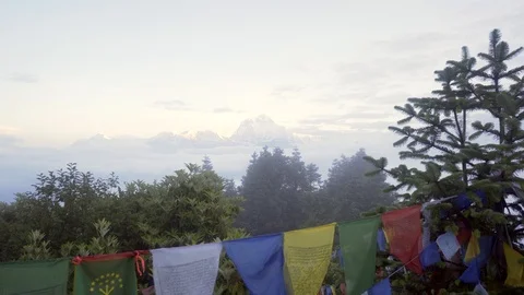 Low to high of prayer flags to reveal Himalayan mountains above the clouds Video stock 91434304