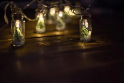 Low key Image of christmas tree in mason jar with garland warm lights next to Stock Photos