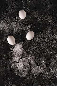 Low key image of a white eggs and a heart shaped imprint on black background Stock Photos