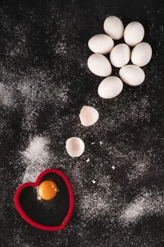 Low key image of a white raw organic eggs on black background sprinkled with Stock Photos
