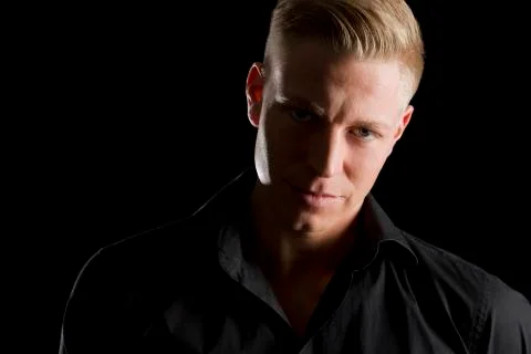 Low key portrait of young alluring man looking straight. Stock Photos