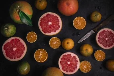 Low key top view of citrus fruits background. Mix of cutted grapefruits and m Stock Photos