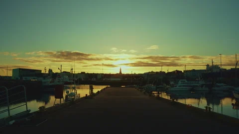 Low-key wide shot of a harbor pier leading to the silhouette of Hallgrimski.. Stock Footage 328460550