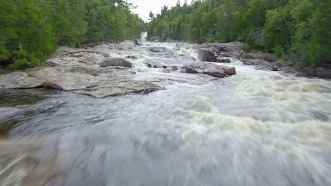Low level aerial drone shot of raging river in a forest Stock Footage 79606581