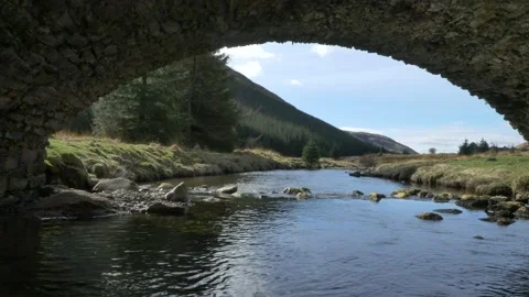 Low level drone flight and lift, along river, under archway of bridge Stock Footage 169248743