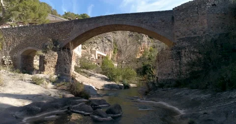 Low-level drone flight in stream and woman with mask crossing stone bridge Stock Footage 146968023
