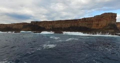 Low level fight approaching Waves Breaking on a rugged cliff shoreline Video stock 92843540