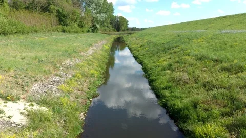 Low level flight above artificial water channel towards rusty bridge Stock Footage 129468272