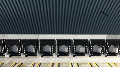 Low-level oblique aerial view tracking past active freight loading docks and Stock Footage 340898098