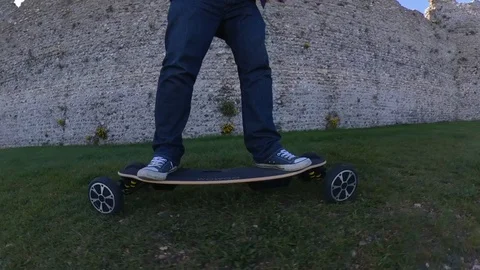 Low level parallax shot of a man riding an electric skateboard, and coming Video stock 107002014