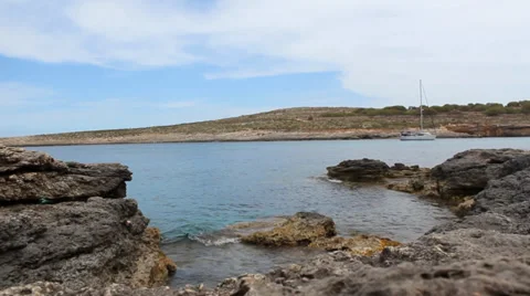 Low Level Shot, Grey Rocky Rocks With Slow Sea Waves Moving And Boat Vidéo 34256089