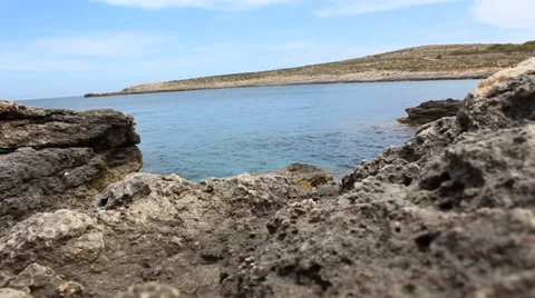 Low Level Shot, Grey Rocky Rocks With Slow Sea Ripples Moving With Blue Sky Vidéo 34256235