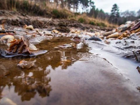 Low level view of puddle water in gully with stones Stock Photos