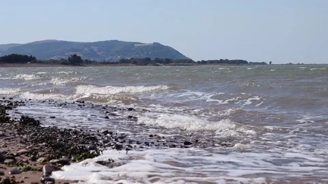 Low level view of waves breaking on the beach at Blue Anchor in Somerset, UK. Stock Footage 135180688