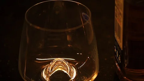 Low light footage of bourbon, cognac or whiskey poured in wine glass. Stock Footage 113736814