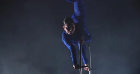 Low lighting in the studio, woman is doing a split on top of a spinning hoop, 4k Stock Footage 162885754