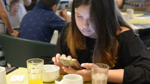 Low ligth selective focus. Beautiful little girl playing with smartphone anf dri Video stock 106351880