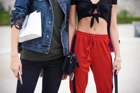 Low mid section of two trendy young women standing in park Stock Photos