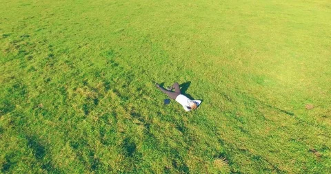 Low orbital flight around man on green grass with notebook pad at yellow rural Video stock 127343228
