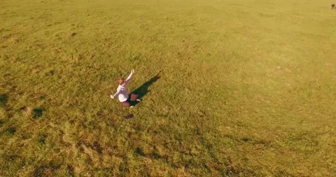 Low orbital flight around man on green grass with notebook pad at yellow rural Stock Footage 294488049