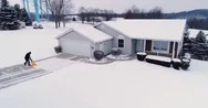 Low Orbiting Aerial View Of Homeowner Shoveling Show From Driveway Stock Footage
