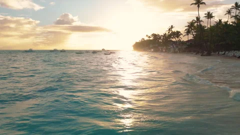 A low pass over turquoise waves washing a sandy resort beach in Punta Cana Stock Footage 316245478