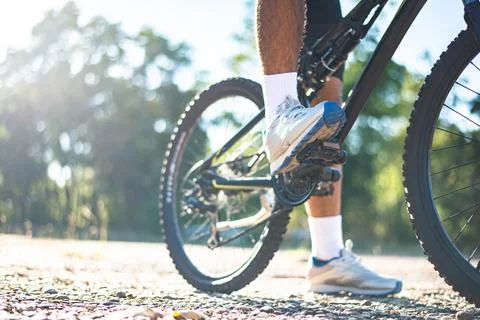 A low perspective of mountain cyclists on a rocky path at sunset Focus on sho Stock Photos