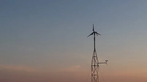 Low-power wind generator - rotating blades on the mast - colorful sky Stock Footage 275559206