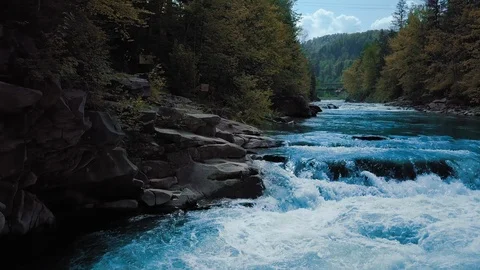 Low rapid flight over the rushing mountain river and waterfall, blue in the Stock Footage 92132069