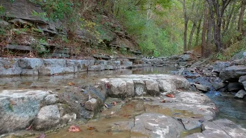 Low reverse flight over rocky creek bed of small stream in forest Stock Footage 118620813