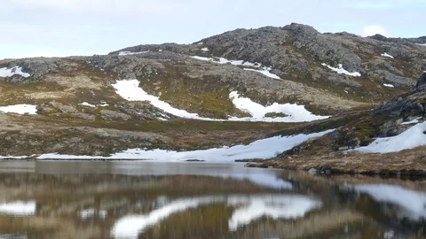 Low rocky mountains are reflected in the calm water of a small lake. Video stock 81727103