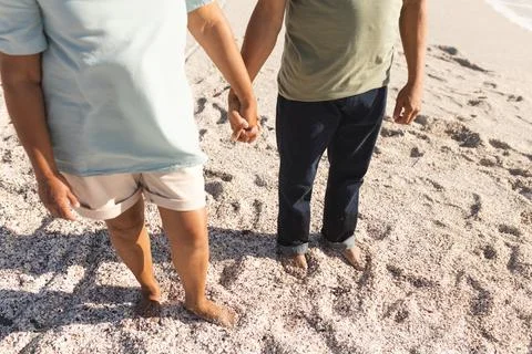 Low section of active senior multiracial couple holding hands while standing on Stock Photos