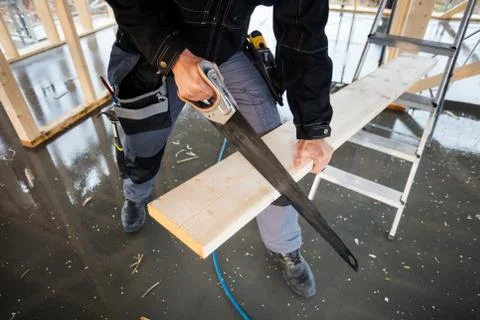 Low Section Of Carpenter Using Hand Saw To Cut Plank Stock Photos