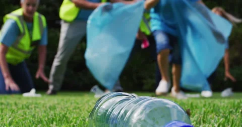 Low section of caucasian boy running and picking up litter with a group of Stock Footage 150853393
