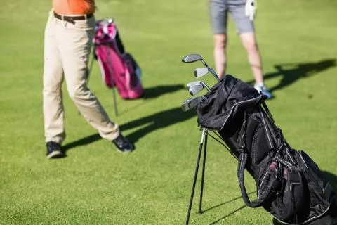 Low section of couple playing golf with bag on foreground Fotos Stock