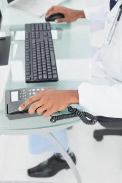 Low section of doctor using computer at medical office Fotos de archivo