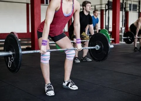 Low Section Of Female Trainer Lifting Barbell 写真素材