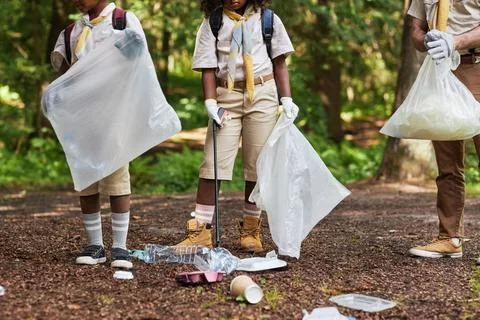 Low section of group of scouts picking up trash in forest Foto stock