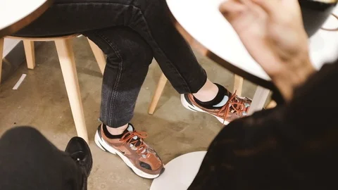 Low section handheld shot of two women sitting in cafe Stock Footage 122511940