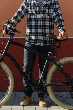 Low section of man with bicycle standing on sidewalk against building during Fotos de archivo