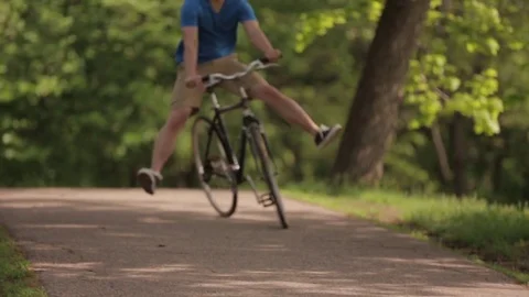 Low section of man with feet up riding bicycle at park Stock Footage
