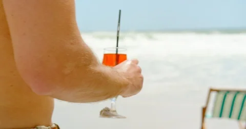 Low section of man holding cocktail drinks at beach 4k Stock Footage 102581403