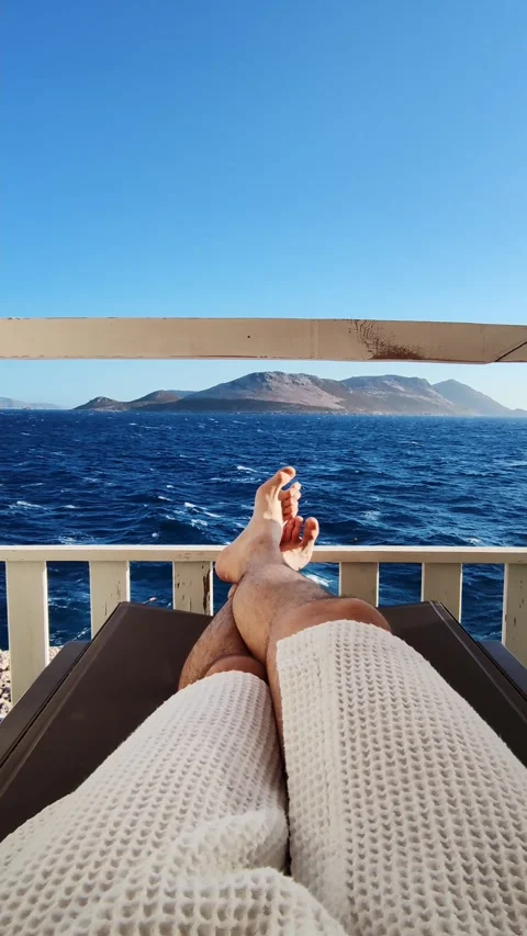 Low section of man legs lying on sunbed situated on dock with serene seascape Stock Footage 344043879