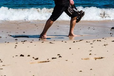 Low section of man walking barefoot on the beach Fotos Stock