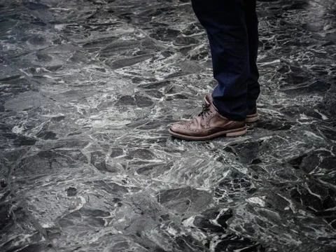 Low section of man wearing smart leather shoes standing on marble floor indoors Stock Photos